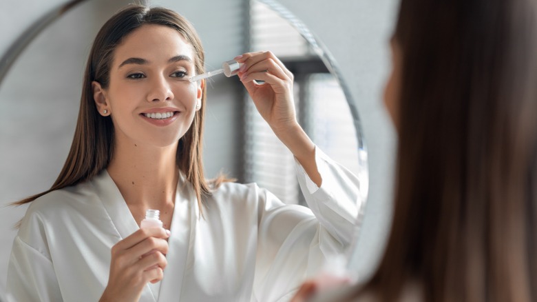 Woman applies serum to face