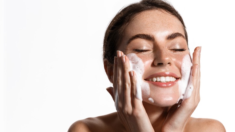 woman washing face with cleanser