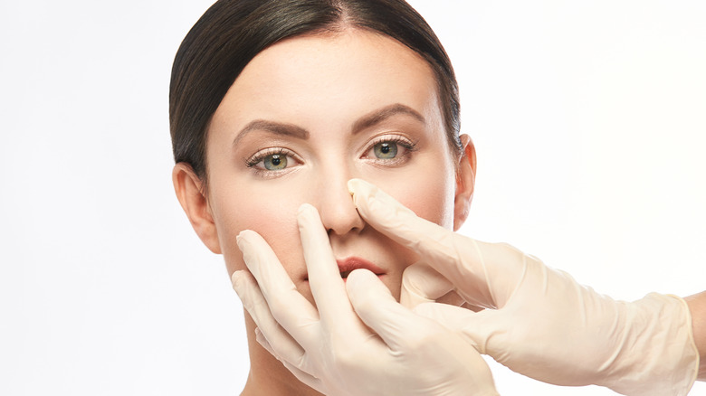 Gloved hands touching model's face