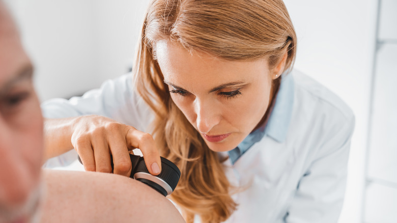 dermatologist looking closely at her patient's skin