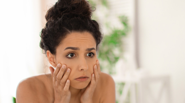 worried woman looking in mirror