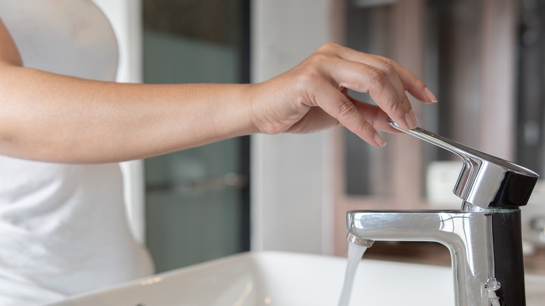 woman turning on water faucet