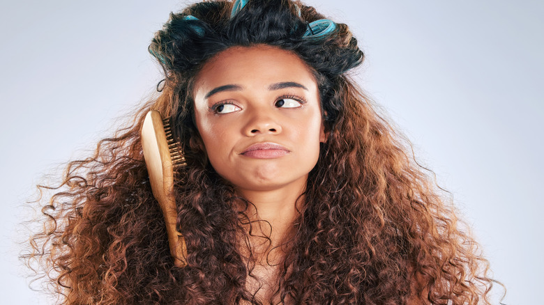 Upset woman with curlers, brush