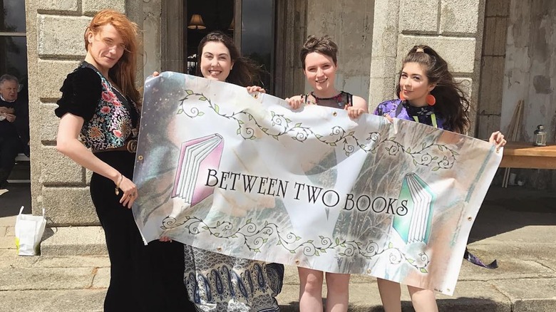 Florence Welch and others holding up a banner for her platform Between Two Books"