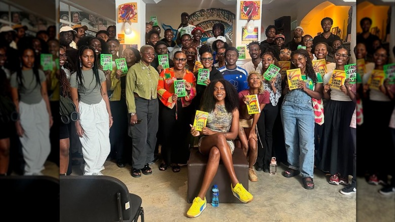 Noname posing with their book club holding up their books