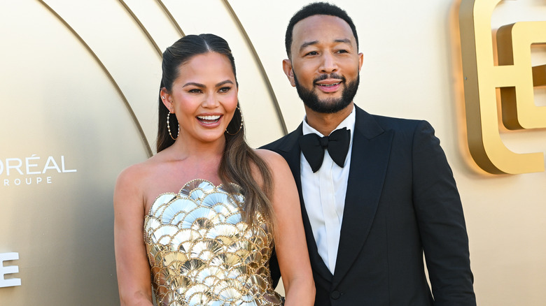 Chrissy Teigen and John Legend smiling together on a red carpet