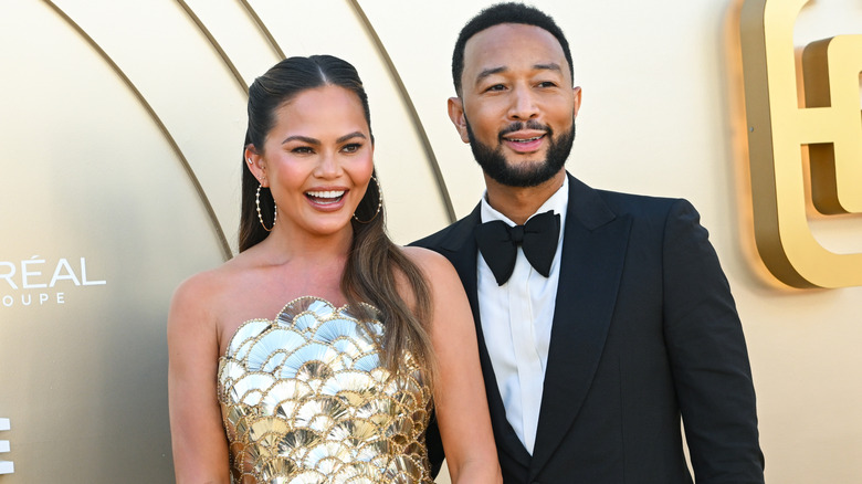 Chrissy Teigen and John Legend smiling together on a red carpet