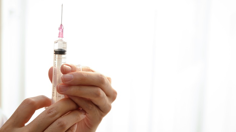 Closeup of doctor holding syringe of clear liquid
