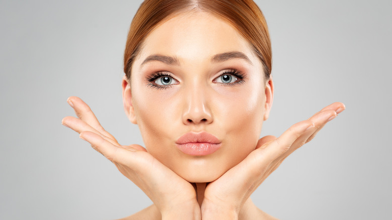 woman holding hands under face