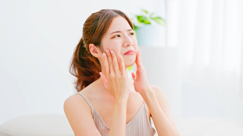 unhappy woman touching cheeks