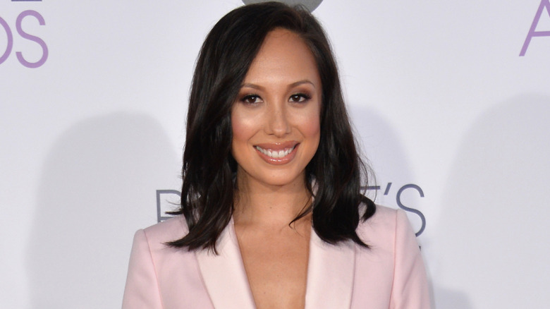 Cheryl Burke smiles while walking an award show red carpet