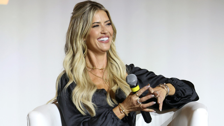 Christina Haack laughing and holding a microphone