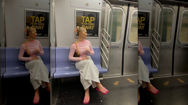 Girl wearing a pink top with a white column skirt.