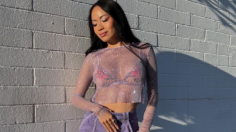 Woman wearing purple jeans, mesh top