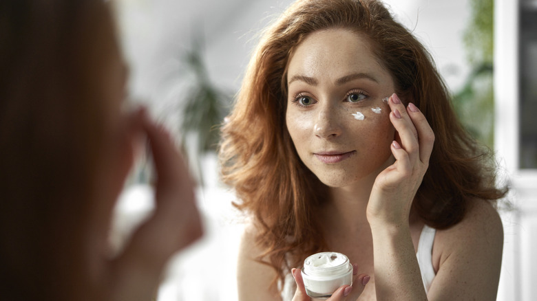 A woman applying skincare