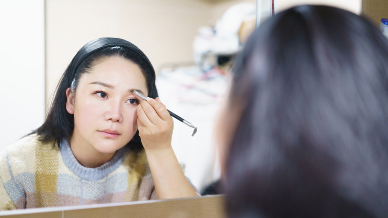 Woman drawing her eyebrows in the mirror