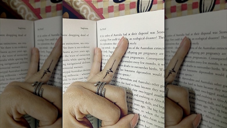 person with heartbeat tattoo on ring finger