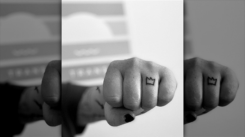 person with crown ring finger tattoo