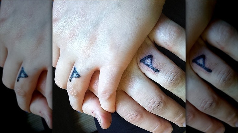 couple wearing ring finger tattoos