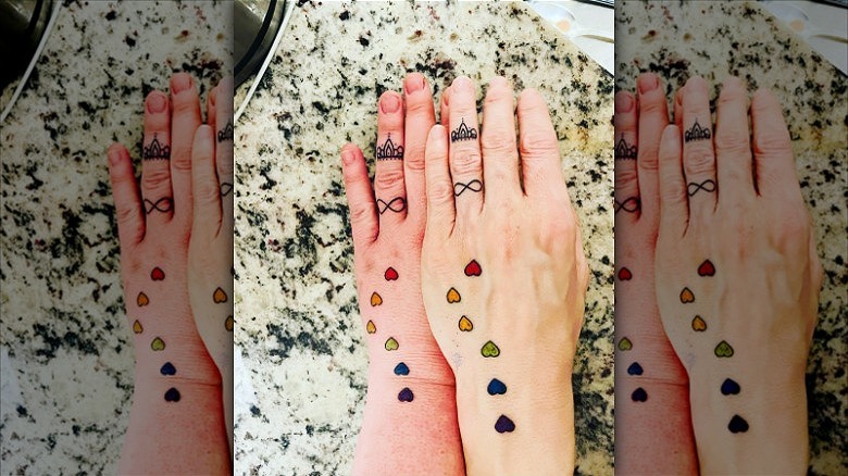 couple wearing infinity ring finger tattoos