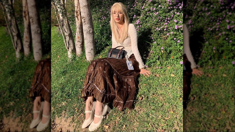 Woman with bangs sitting in grass