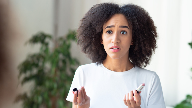woman looking at makeup concerned