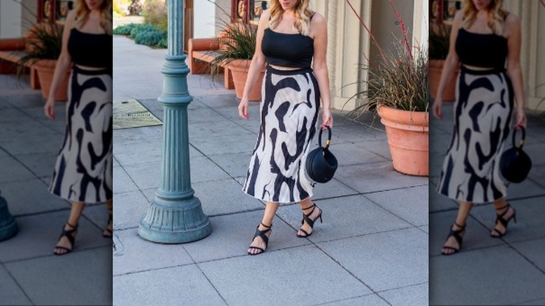woman with a black tank top and printed slip skirt