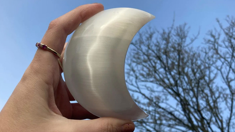 Woman holding selenite moon shape