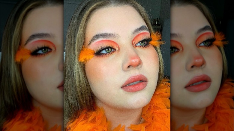 A woman with orange feathers on her eyes