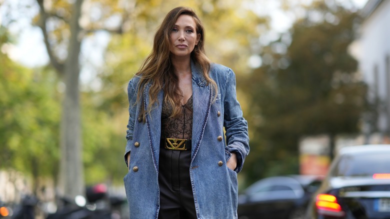 Woman wearing sheer floral bodysuit, denim blazer