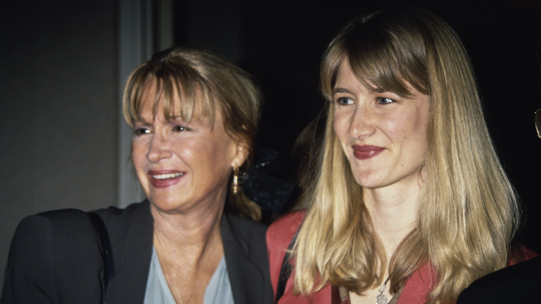 Diane Ladd wears a black jacket and a ponytail while photographed next to daughter Laura Dern sporting a red jacket and shoulder-length hair.