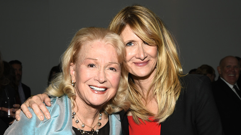 Laura Dern is seen with her arm around mother Diane Ladd as they lean their heads together and smile.