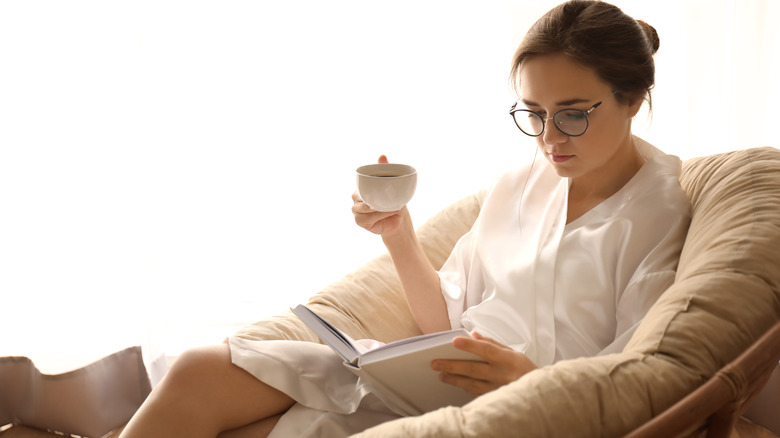 Ill woman rests in robe with tea