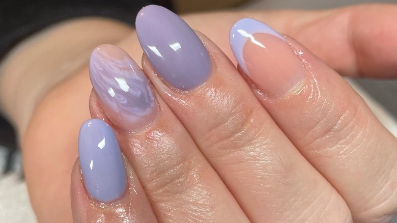 hand with mismatched nail designs 