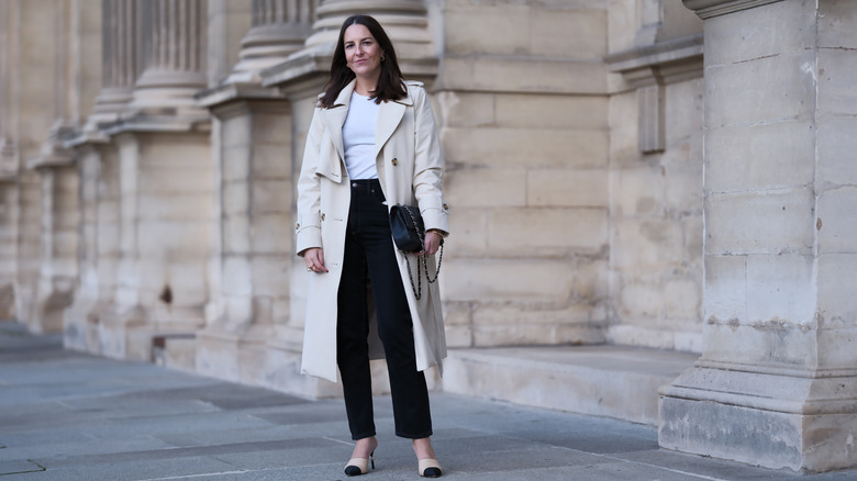 Woman in black straight jeans and white coat