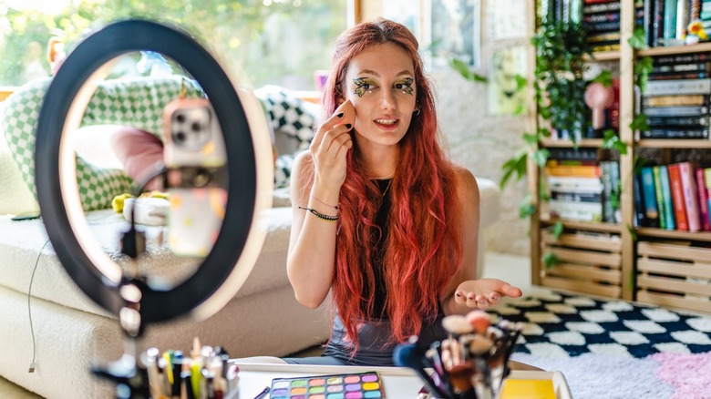 Woman applying makeup with phone and ring light