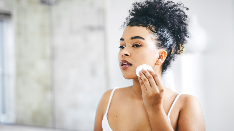 woman using cotton pad on face
