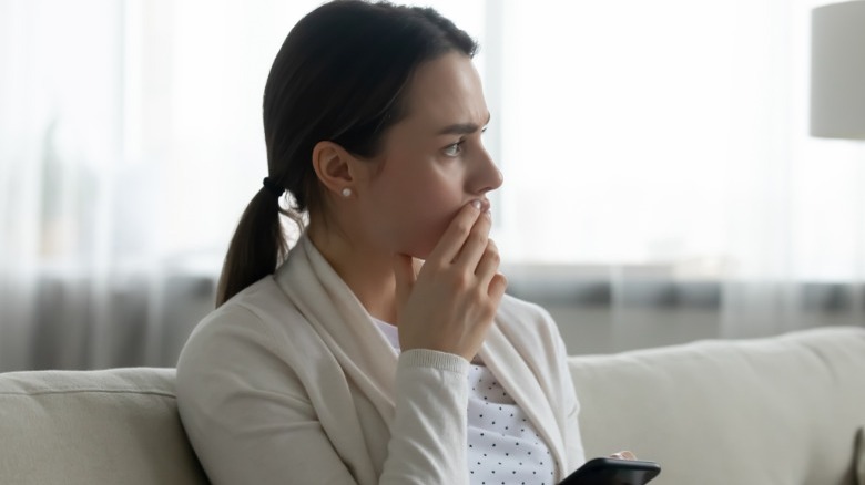 Woman thinking while holding phone