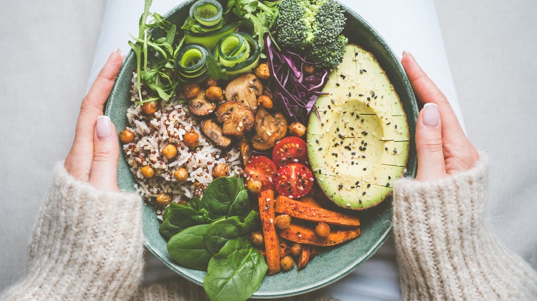 Hands holding bowl of salad