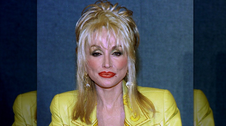 Dolly Parton wearing a yellow jacket with piecey hair