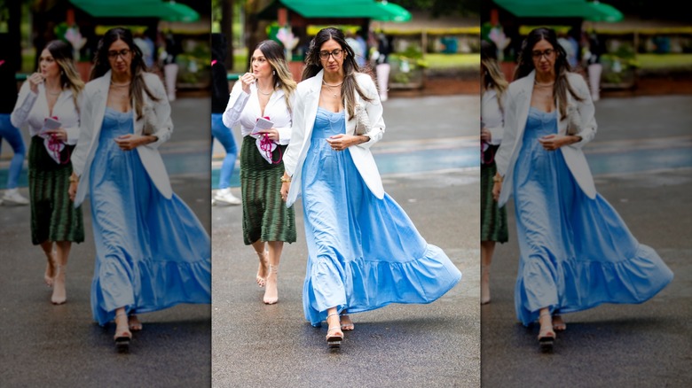 A woman wearing a blue maxi dress walks