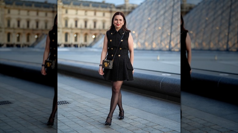 A woman wearing a black mini dress and black sheer tights