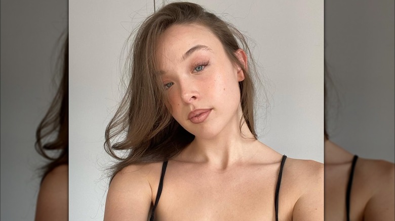 Ella Beatty taking a selfie, wearing a black top with minimal makeup applied