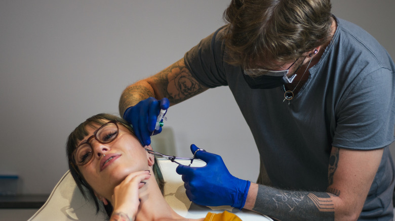 Woman getting ears pierced
