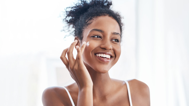 smiling woman applying skincare product