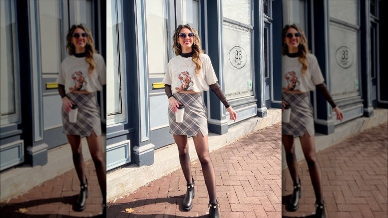 A woman wearing a skirt with a turtleneck and a graphic tee