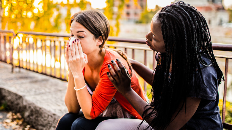 Woman comforting another woman outdoors