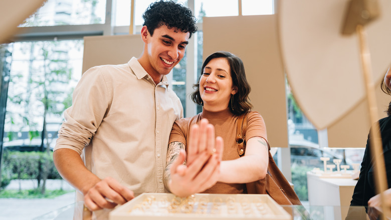 A young couple trying on different rings at a store