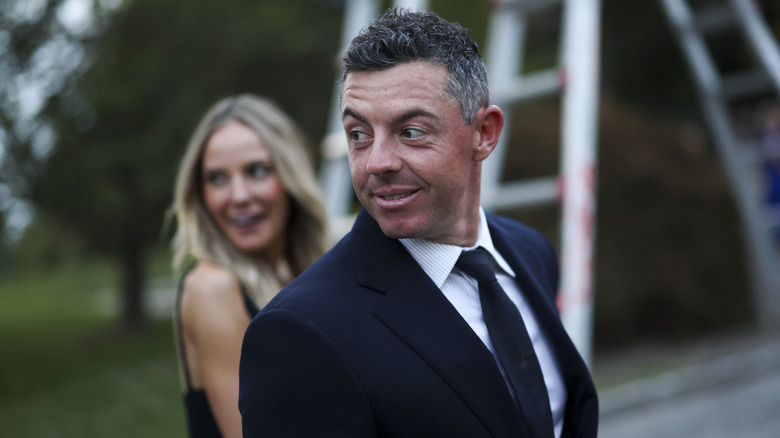 Rory McIlroy looks to his right while holding hands with his wife Erica Stoll