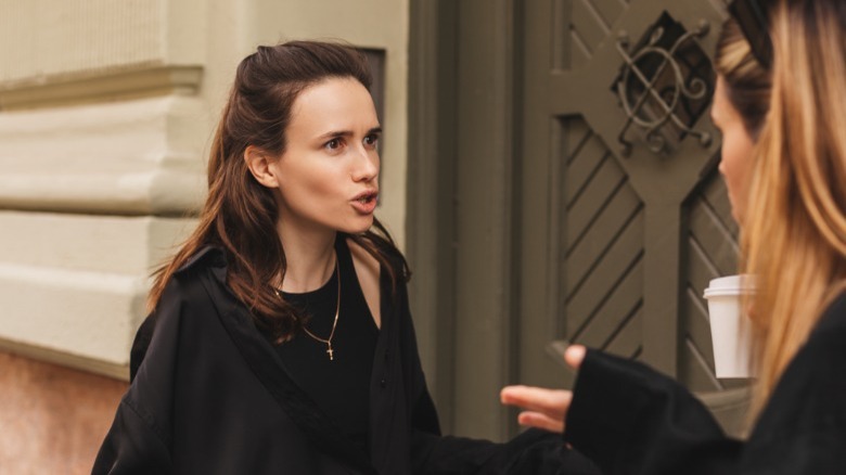 Upset woman talking to woman outside door